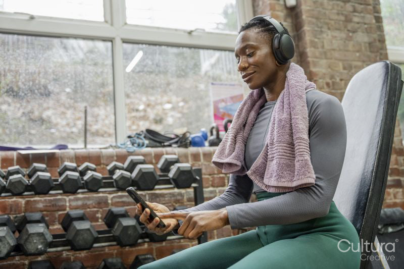 Smiling athletic woman looking at smart phone at gym