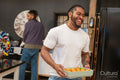 Smiling man holds baked appetizer in pan in kitchen