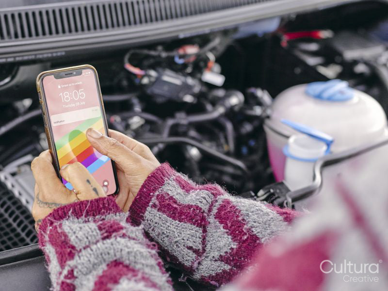 Woman standing over broken car and using phone