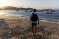 Rear view of man with backpack on beach at sunset