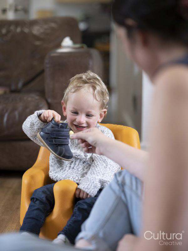 Smiling boy holding shoe and looking at it