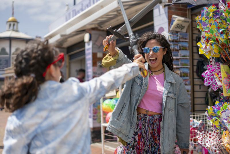 Smiling mother and daughter playing with toy swords