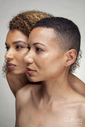 Studio portrait of two shirtless women cheek to cheek
