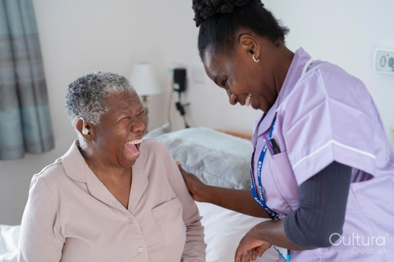 Caregiver and senior woman with hearing aid laughing