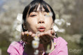 Portrait of young woman blowing flowers