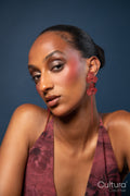 Woman in a burgundy dress and red earrings on a blue background