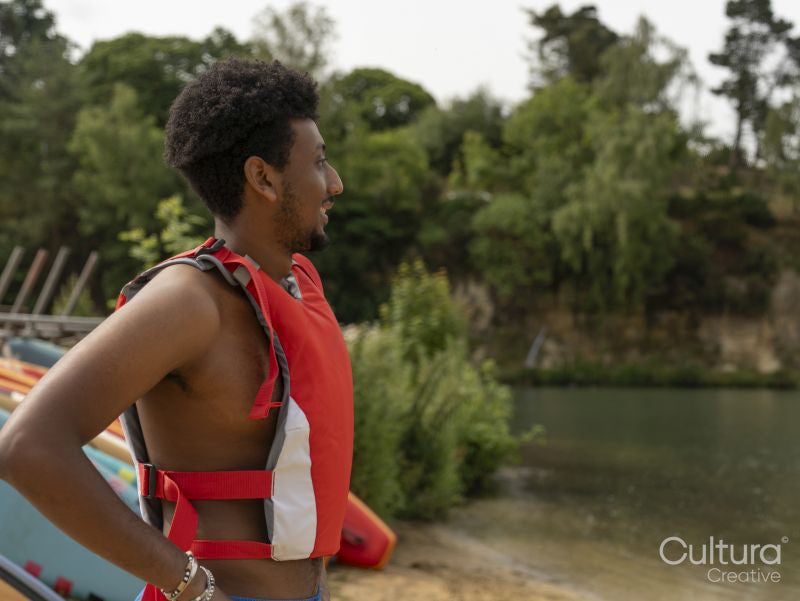 Portrait of smiling man in life jacket looking at lake
