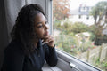 Thoughtful teenage girl looking through window
