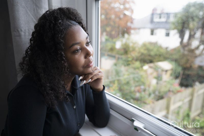 Thoughtful teenage girl looking through window