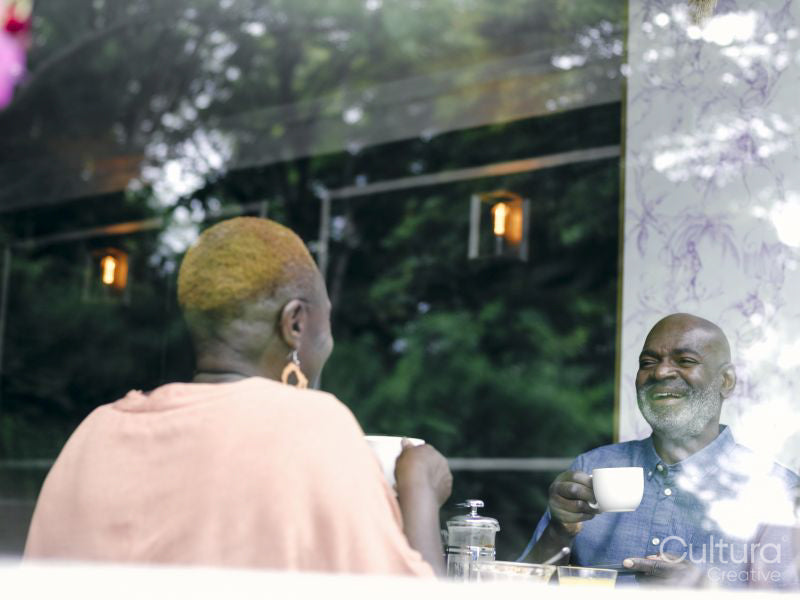 Mature couple enjoying hotel breakfast table seen through window