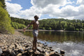 Shirtless man basking on rocky lakeshore, Yorkshire, UK
