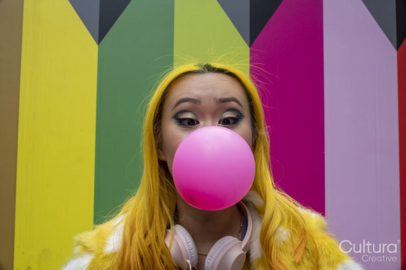 Young woman with yellow hair blowing bubble gum