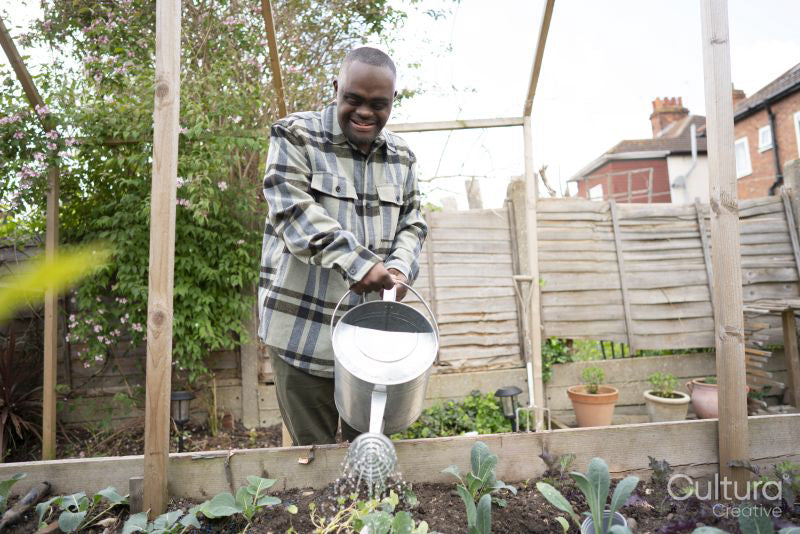 Man with Down syndrome watering plants in garden