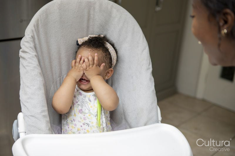 Baby girl playing peekaboo with mother