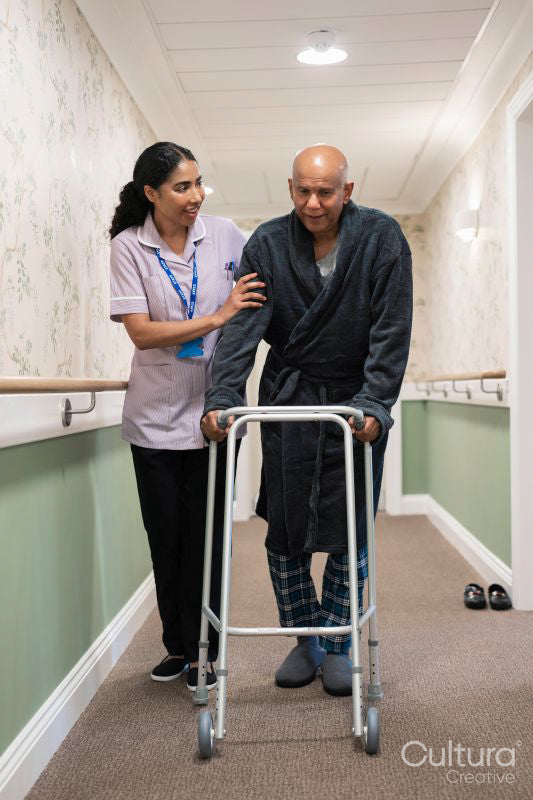 Nurse helping senior man to walk with mobility walker at nursing home
