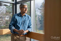 Smiling mature businessman looking through office window