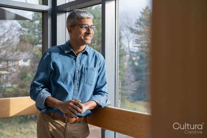 Smiling mature businessman looking through office window