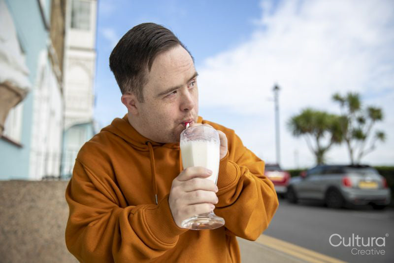 Man drinking milkshake in sidewalk cafe