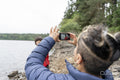Mother photographing son by lake on hike