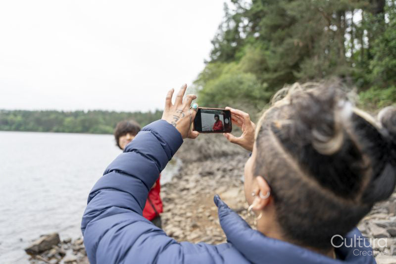 Mother photographing son by lake on hike