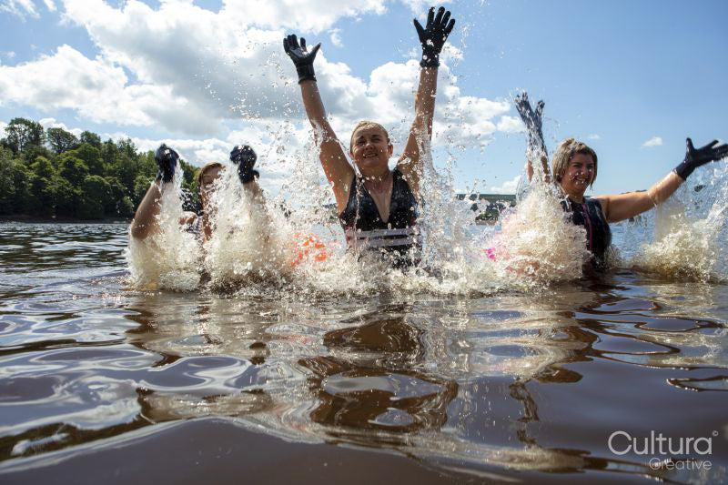 Female friends splashing water in lake, Yorkshire, UK
