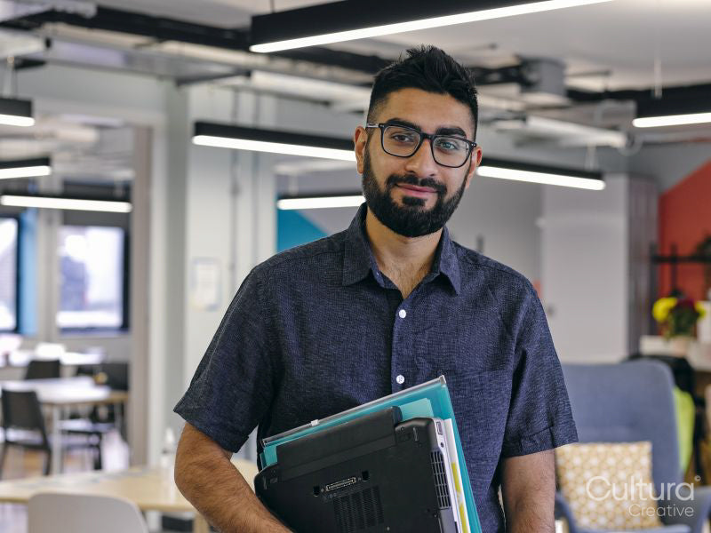 Portrait of man holding laptop in office