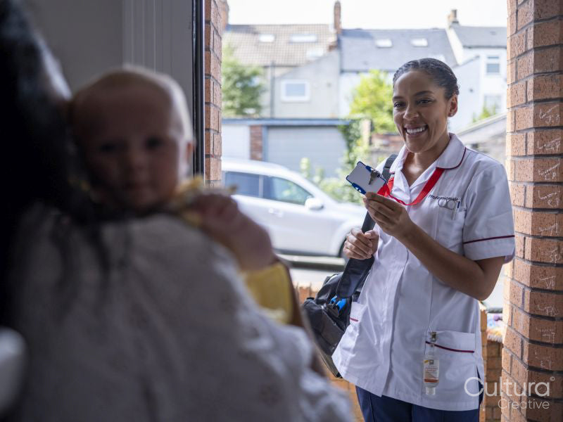 Nurse visiting woman with baby girl at their home, showing ID