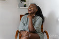 Portrait of young woman laughing while sitting in armchair at home