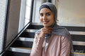 Portrait of smiling woman wearing headscarf sitting on steps