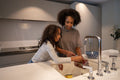 Smiling mother and daughter washing red grapes in kitchen