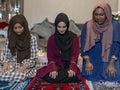 Women kneeling on prayer mat during Ramadan celebration at home