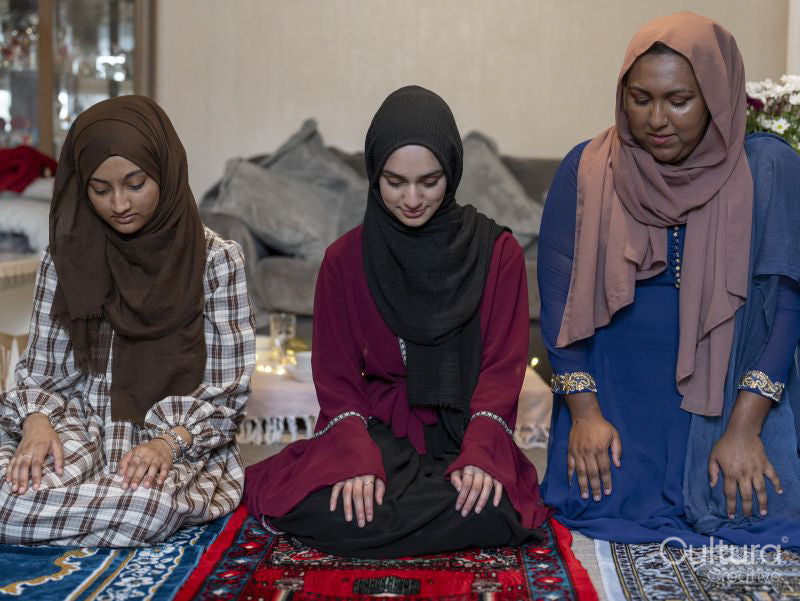 Women kneeling on prayer mat during Ramadan celebration at home