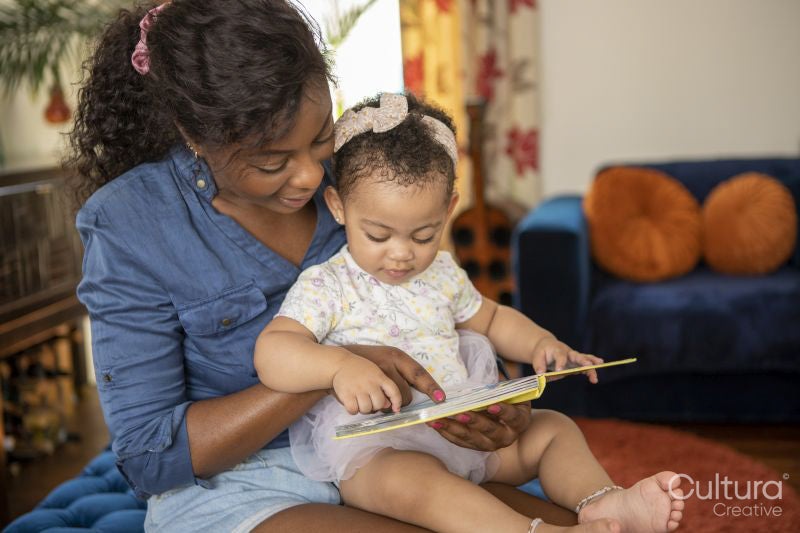 Mother reading to baby daughter at home
