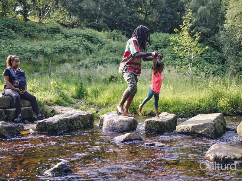Father and daughter walking on rocks shallow creek