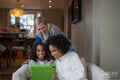 Smiling women with daughter looking at digital tablet at home