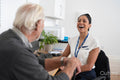 Female doctor and senior patient talking and laughing in office