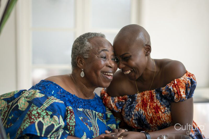 Smiling senior woman with adult daughter laughing at home