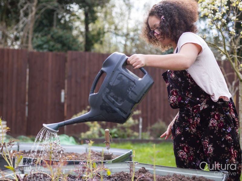 Girl watering plants in backyard