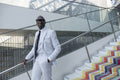 Confident man wearing white suit standing on colorful steps