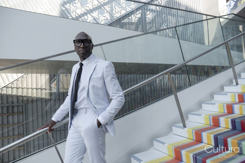 Confident man wearing white suit standing on colorful steps