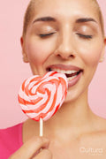 Young blond woman biting heart shape lollipop