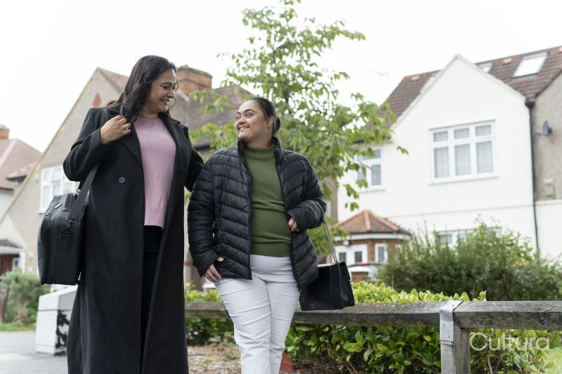 Mother walking with down syndrome daughter in residential district