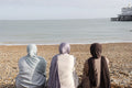 Three Muslim women looking at sea while sitting on beach