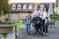 Senior man sitting in wheelchair surrounded by family and care giver outside retirement home