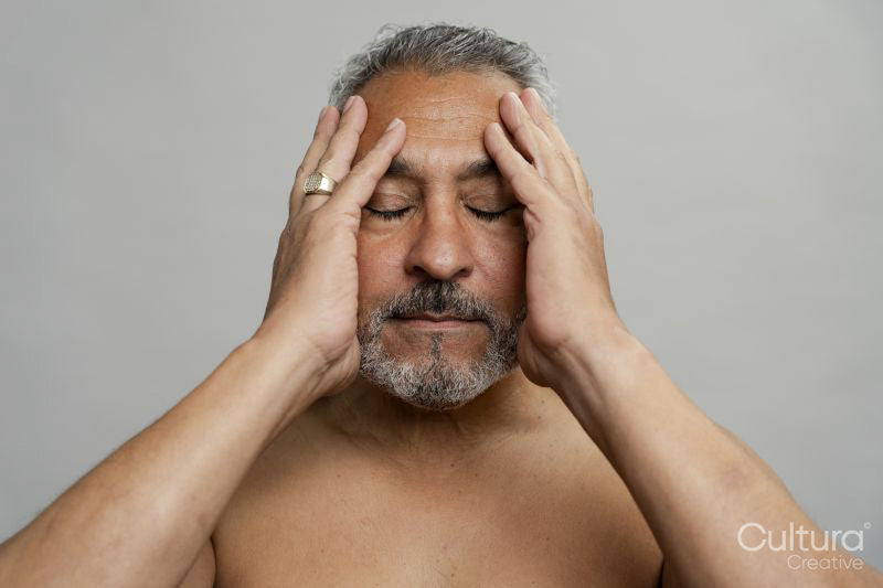 Portrait of serious man meditating against gray background