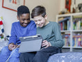 Boy friends using digital tablet at home