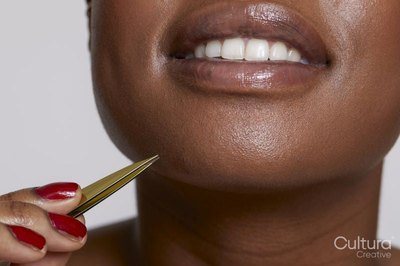 Close-up of smiling woman with tweezers