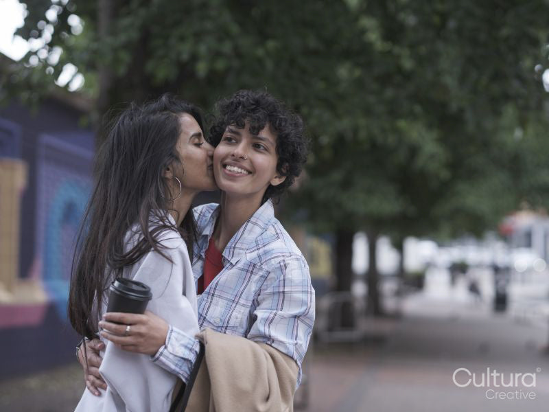 Female couple hugging and kissing in street