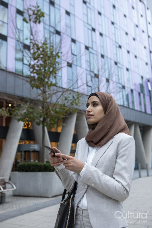Businesswoman in hijab with smart phone in city