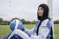 Portrait of woman in hijab sitting in soccer field with soccer ball